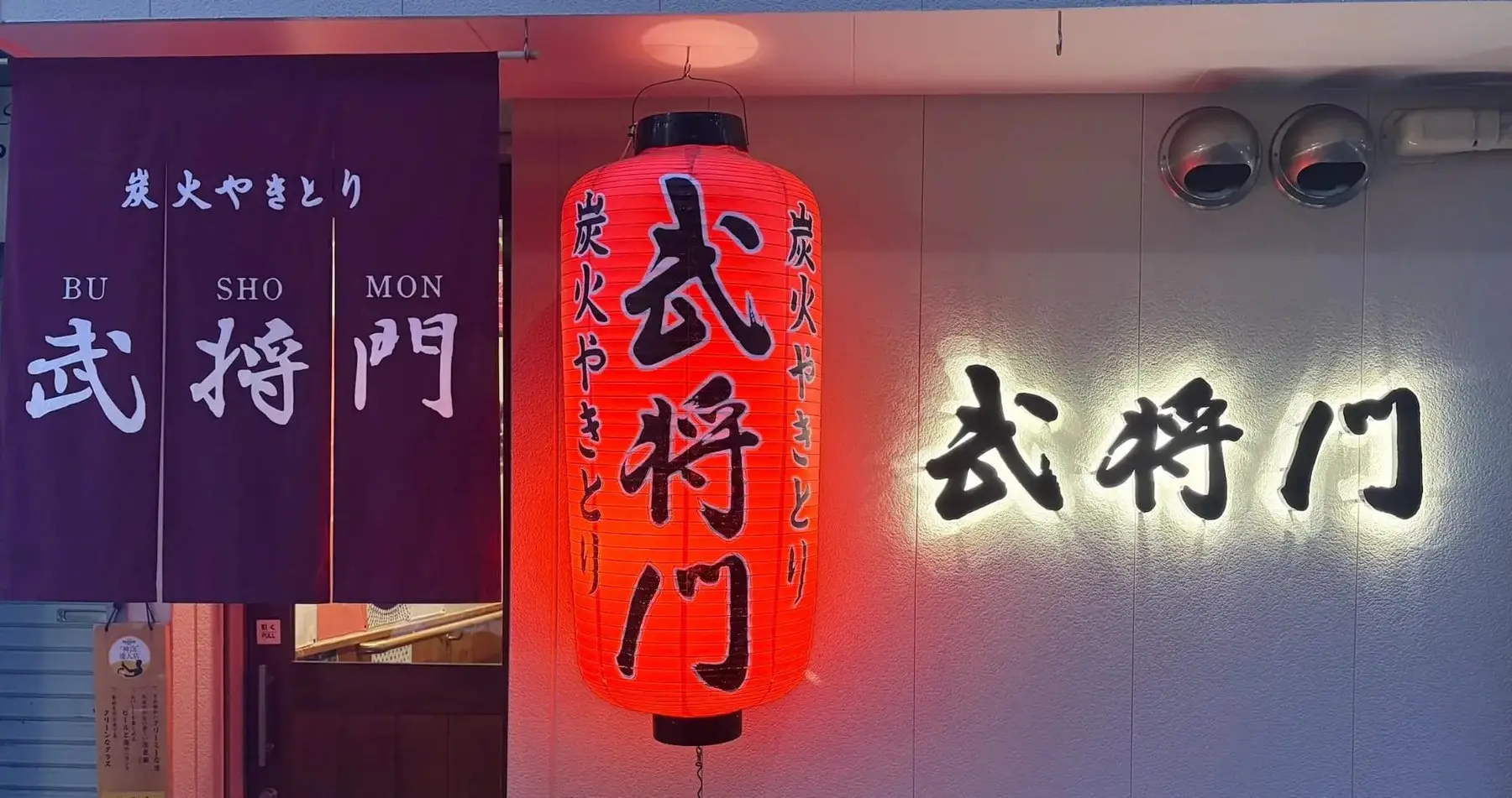 紫の暖簾と赤提灯の店構え