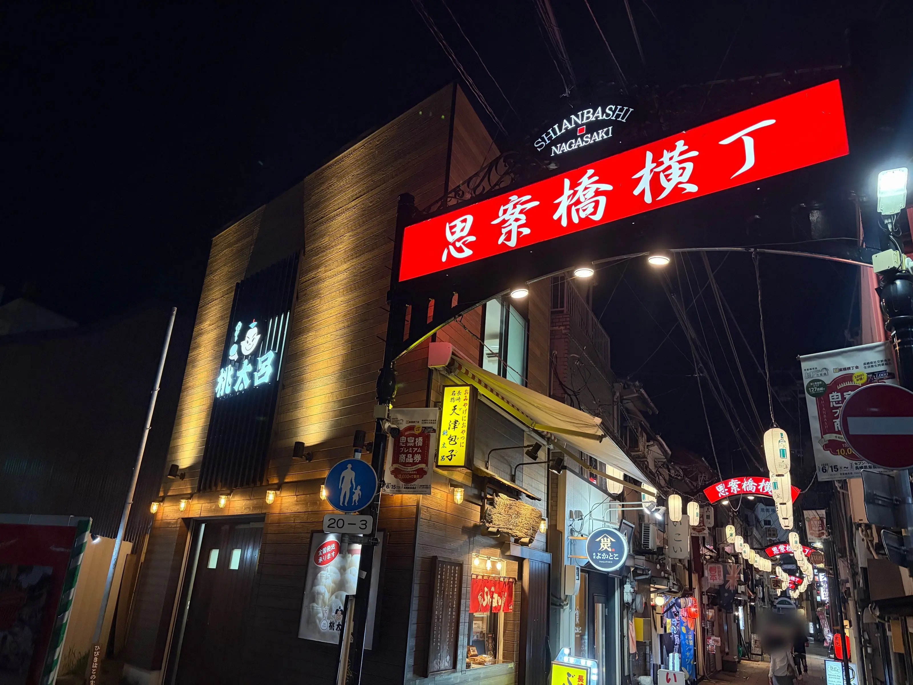 The entrance of Shianbashi Yokocho at night: the glowing red sign on the arch, with the lantern-lit alley beyond