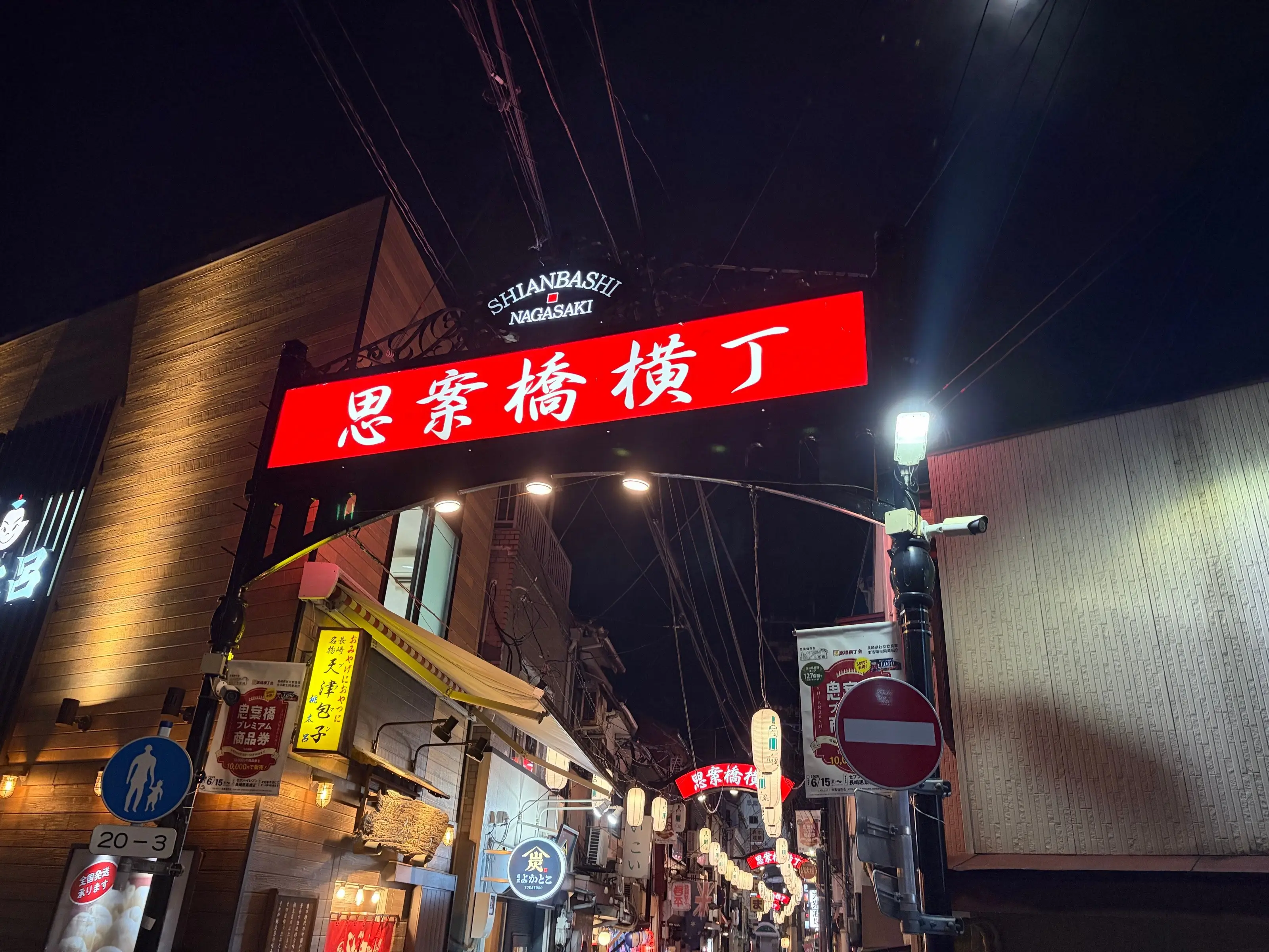夜の思案橋横丁の入口。赤く光る「思案橋横丁」の看板のアーチの奥に、提灯の路地が続いている